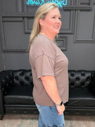 Woman standing in a room with a black leather couch and decorative elements.