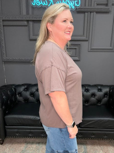 Woman standing in a room with a black leather couch and decorative elements.