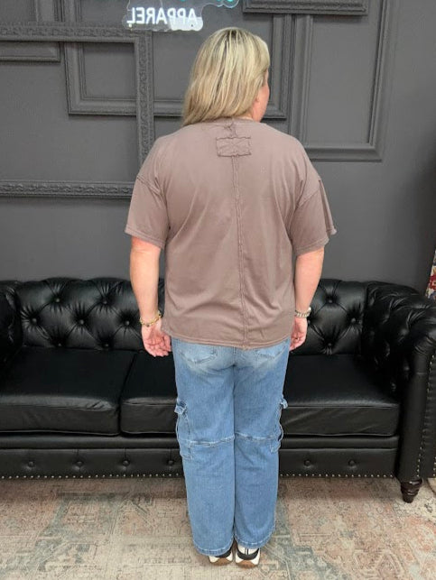 Person standing in front of a black leather sofa with a gray wall and decorative elements in the background.