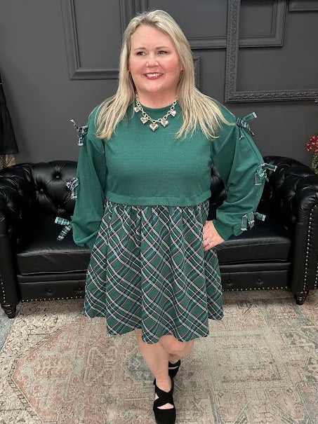 Woman in green top and patterned skirt standing in a store with Christmas decorations.