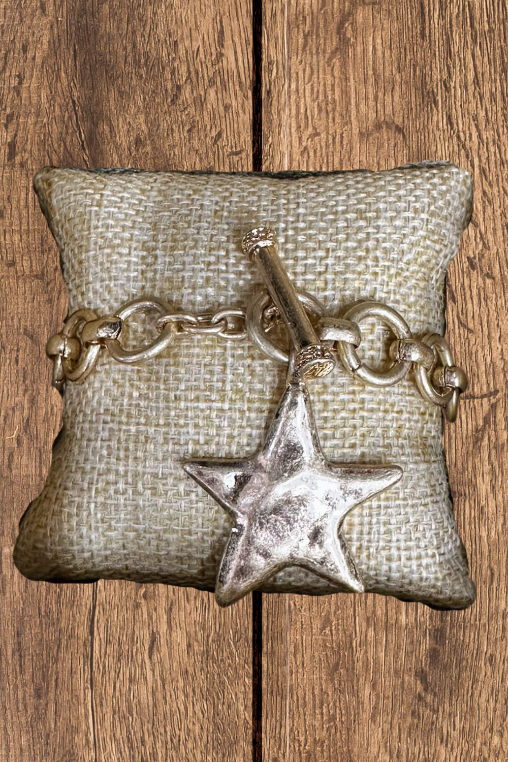 Bracelet with star charm on a textured pillow against a wooden background