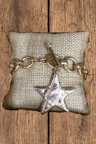 Bracelet with star charm on a textured pillow against a wooden background
