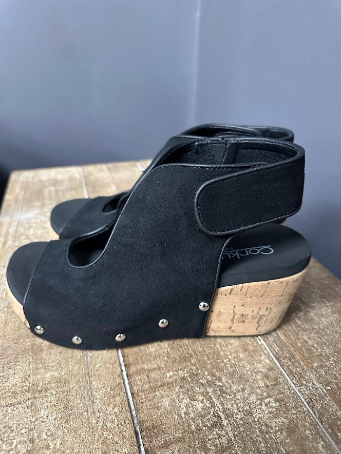 Black wedge sandals with cork sole on a wooden surface