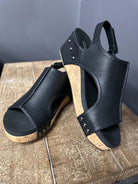 Black wedge sandals with cork sole on a wooden surface
