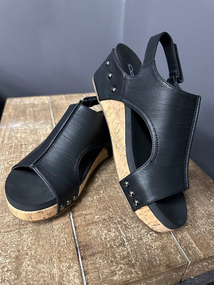Black wedge sandals with cork sole on a wooden surface
