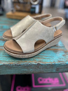 Silver sandal with brown sole on a blue wooden surface