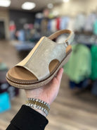 Hand holding a sandal with a blurred store interior background