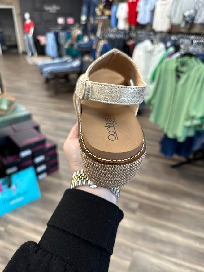 Gold sandal with rhinestone sole held in a clothing store.