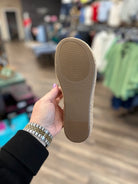 Person holding a brown shoe sole with 'Celine' branding in a store setting.