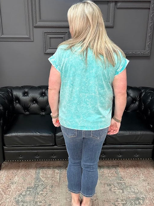 Person wearing a light blue t-shirt and jeans standing in front of a black leather couch.