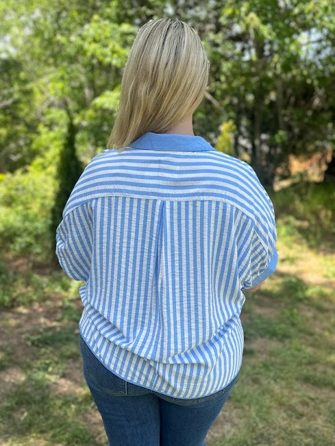 Person wearing a blue and white striped shirt in an outdoor setting