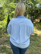 Person wearing a blue and white striped shirt in an outdoor setting