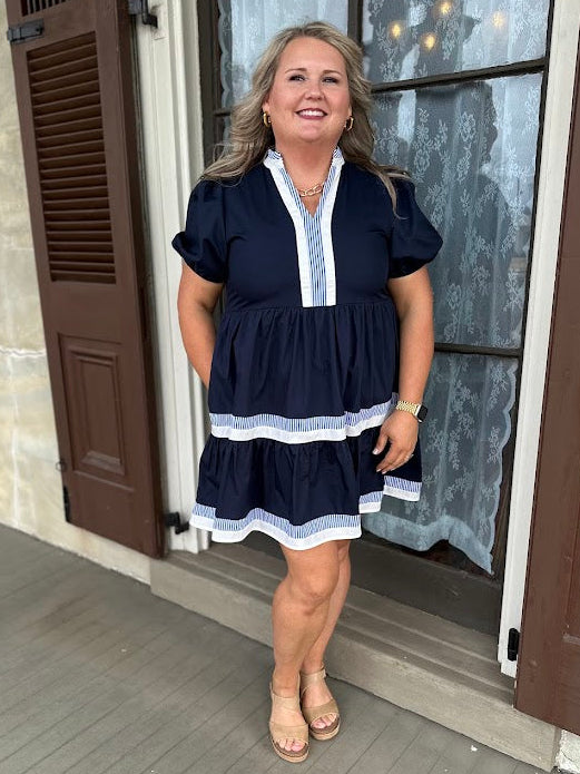 Woman in a navy dress standing on a porch