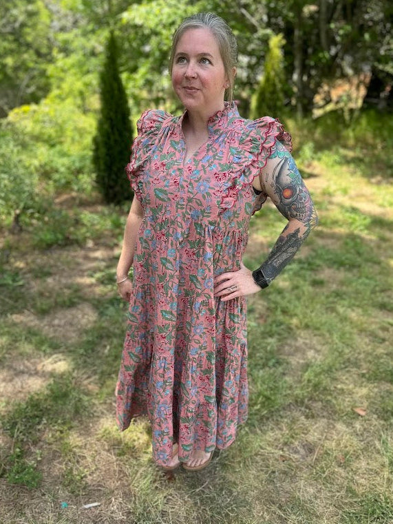 Woman in a floral dress standing outdoors in a garden