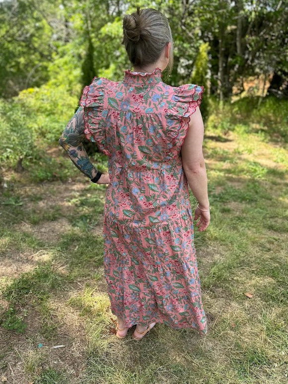 Person wearing a floral dress standing in a grassy outdoor area.