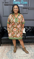 Woman wearing a floral dress standing in front of a black leather couch with 'Gypsy River Apparel' sign.