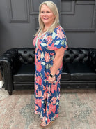 Woman in a floral dress standing in a room with a black leather couch and gray walls.