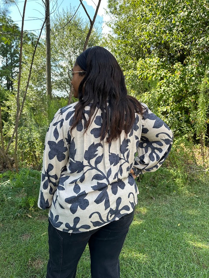 Person wearing a floral-patterned jacket in a forest setting