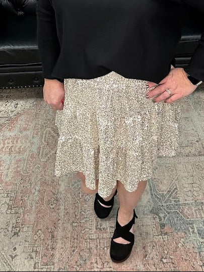 Woman in a black top and patterned skirt standing in a store with Christmas decorations.