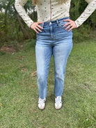Person wearing a floral top and blue jeans standing on grass