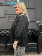 Woman in a black jacket standing in a room with a black couch and 'Gypsy Queen' sign.