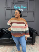 Woman wearing a striped sweater in a room with a black leather couch and gray walls.