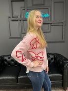 pink bow sweater, holiday sweater, girly knit top, cozy winter sweater, red and pink sweater, boutique knitwear, bow print top, women’s boutique sweater, cute holiday outfit, cozy chic sweater