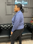 Person wearing a blue jacket standing in front of a black leather couch with 'Gypsy River Apparel' sign.