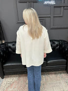 Person wearing a white shirt and blue jeans standing in front of a black leather couch with a Christmas tree in the background.