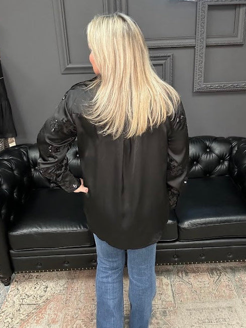 Person wearing a black leather jacket standing in front of a black leather couch with 'Gypsy River Apparel' branding.