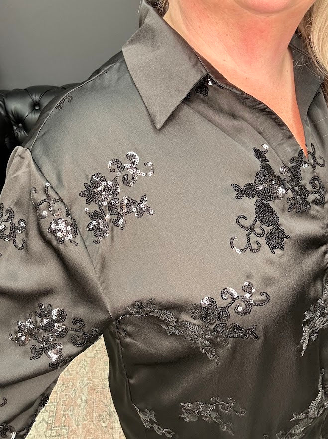 Close-up of a dark gray shirt with floral sequin embellishments on a blurred background
