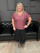 Woman standing in front of a black leather couch with a Christmas tree and 'Gypsy River Apparel' sign in the background.