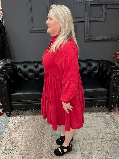 Woman in a red dress standing in a store with a Christmas tree and 'Gypsy River Apparel' sign.