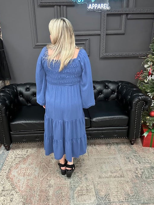 Woman in a blue dress standing in a store with a Christmas tree and 'Gypsy River Apparel' sign.