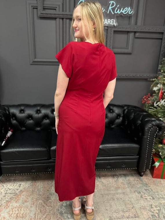 Woman in a red dress standing in a room with a black couch and Christmas decorations.