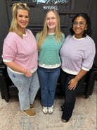 Three women posing together in a store setting with a sign in the background.