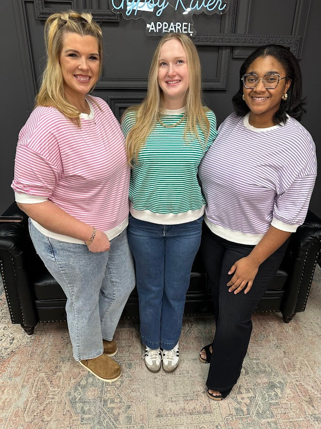Three women posing together in a store setting with a sign in the background.