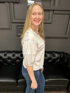 Woman standing in a room with a black leather couch and gray walls.