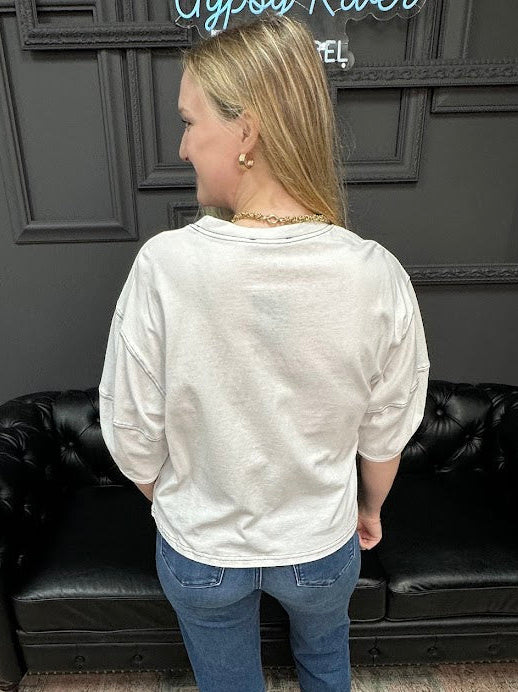 Person wearing a white sweatshirt and blue jeans standing in front of a black leather couch.