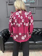 Person wearing a pink floral jacket sitting on a black leather couch.