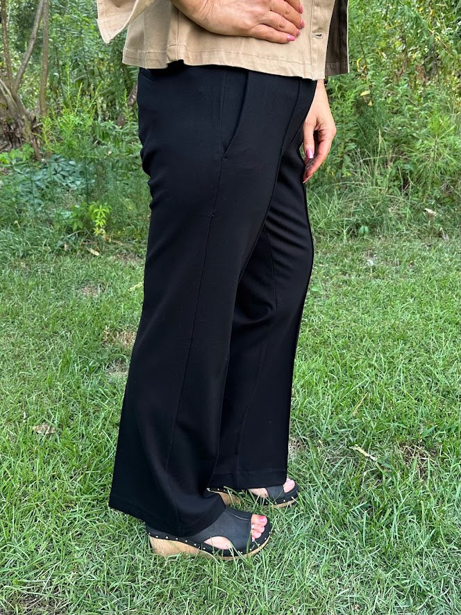 Person wearing black wide-leg pants standing in a grassy area