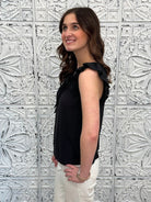 Liverpool black sleeveless blouse with ruffle trim and tie front neckline on model