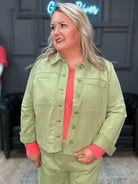 Woman wearing a green outfit with a pink top in an indoor setting