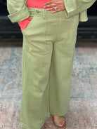 Woman wearing a green jacket and pants with a pink top in an indoor setting.
