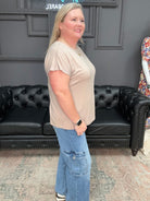 Woman standing in a room with a black leather couch and decorative wall.