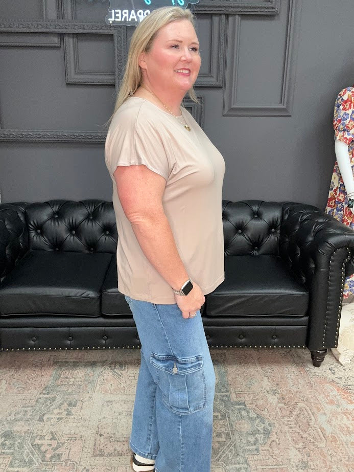 Woman standing in a room with a black leather couch and decorative wall.