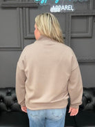 Person standing in front of a black leather couch with a gray wall and decorative elements in the background.