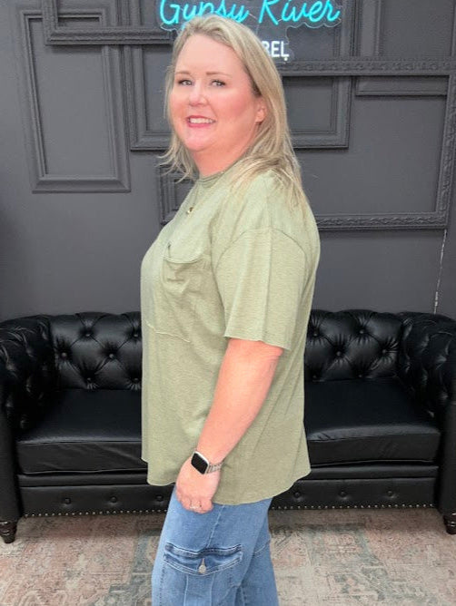 Woman standing in a room with a black leather couch and decorative elements.