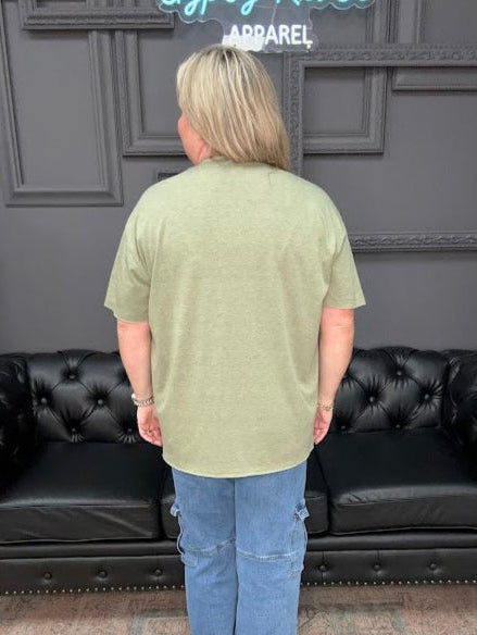 Person standing in front of a black leather sofa with a gray wall and decorative elements in the background.