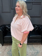 Woman standing in a room with a neon sign and black leather couch.